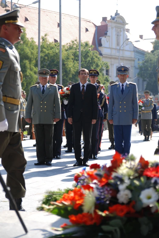 a group of men in military uniform standing near a bunch of flags