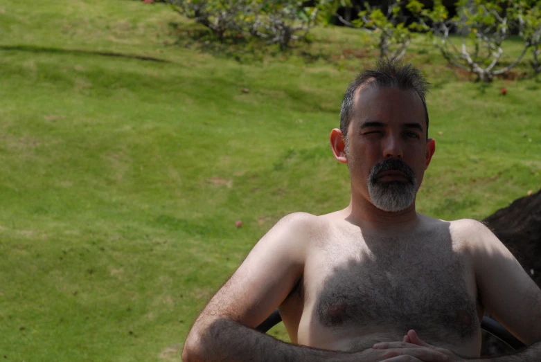 a shirtless man standing on the grass outside