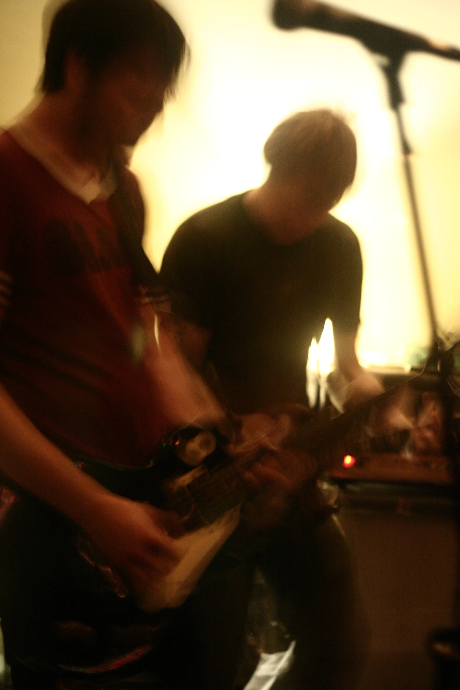 two young men playing guitar in front of microphone