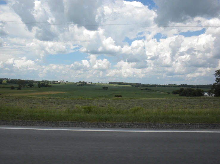 an empty farm land with clouds over the grass