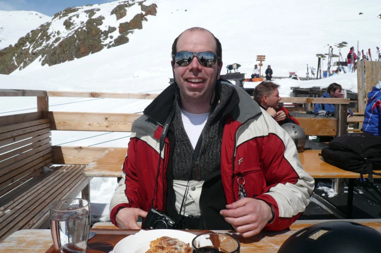 a man sits at an outdoor table eating pizza