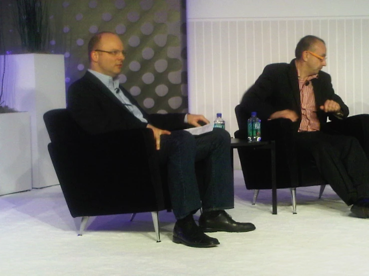 two men sitting in chairs talking on television