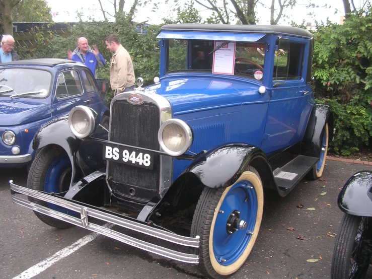 a blue older car is sitting in a lot