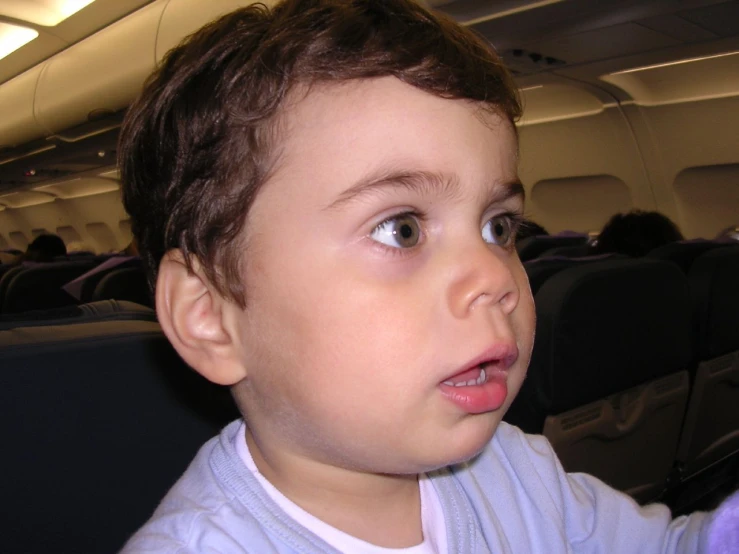 an adorable child standing in the seat on an airplane