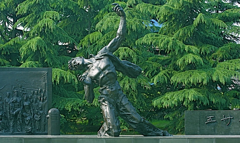 a statue standing in front of a large green tree