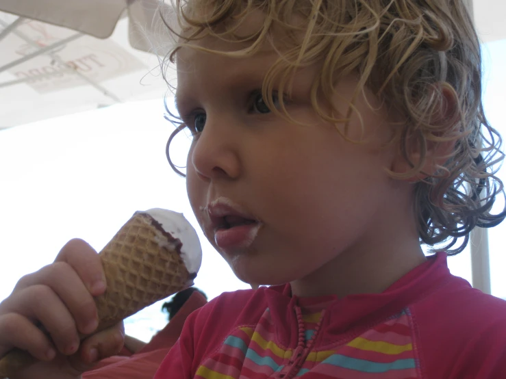 a close up of a child eating a chocolate ice cream cone