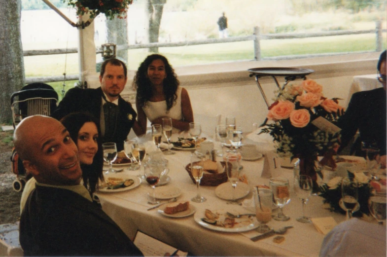 some people sitting around a long dining table with food