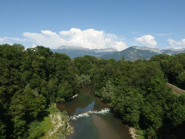 an elevated view of a river surrounded by greenery and mountains