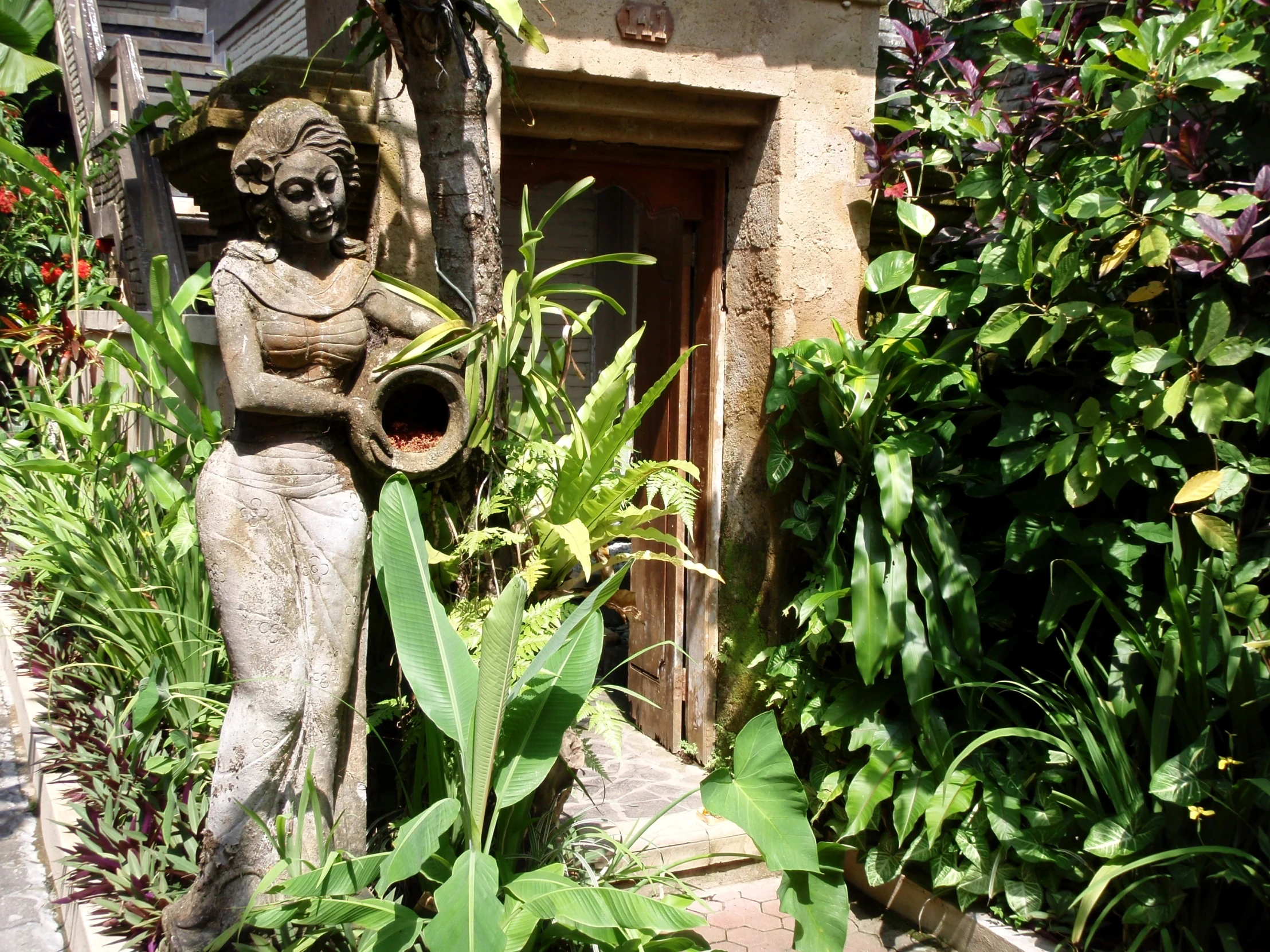 an intricate fountain sits next to lush green plants