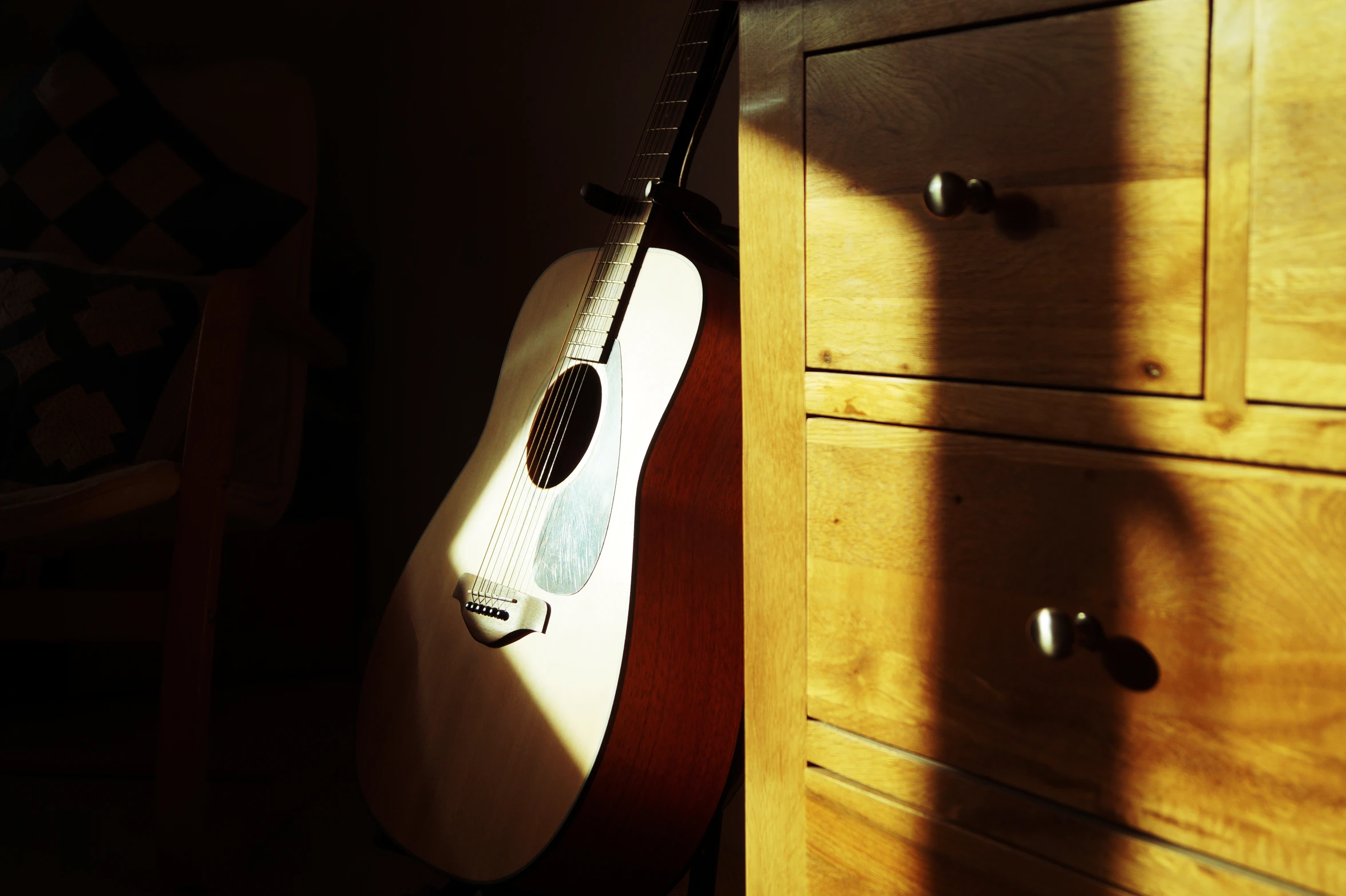 a guitar is in an empty room next to a dresser