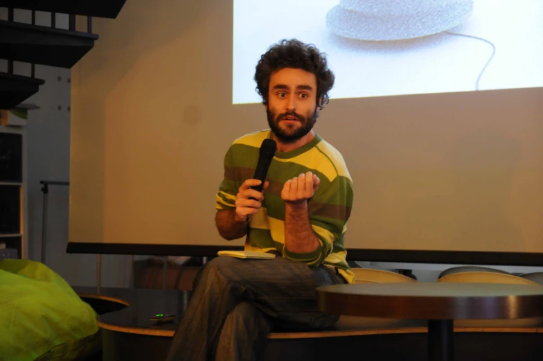 a man speaking in front of a projection screen