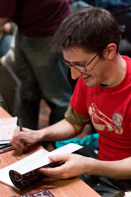 a man writing on a piece of paper at a table