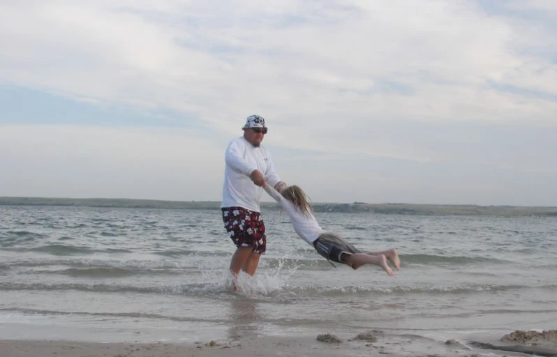 a father and daughter playing on the beach while being silly