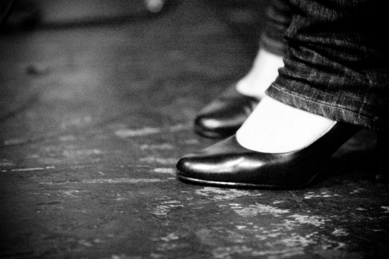 a person with black shoes and white socks standing on a floor