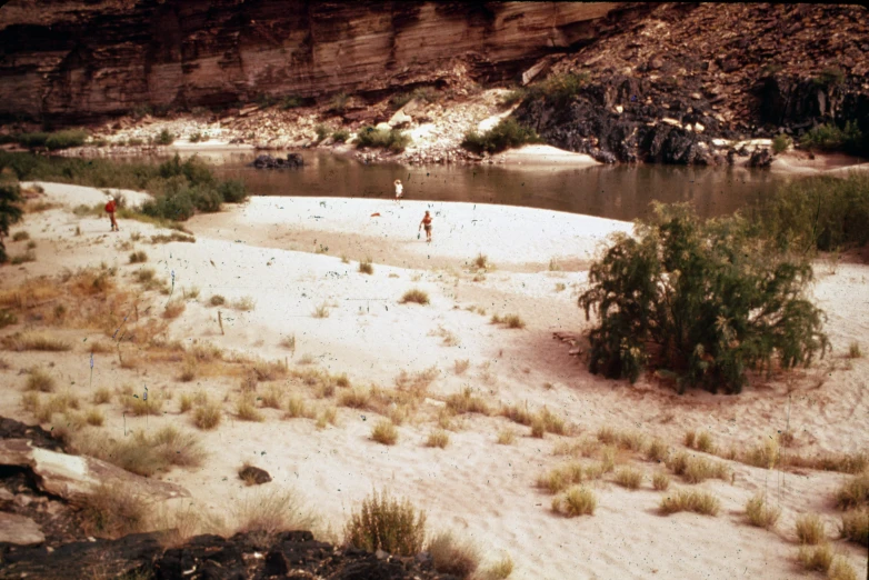 two people walk along a sandy riverbed at low tide