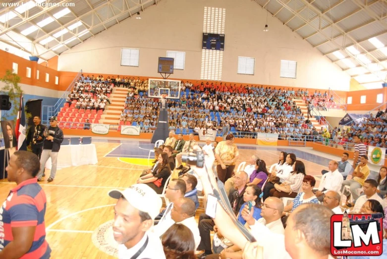 people sitting on a basketball court watching an event