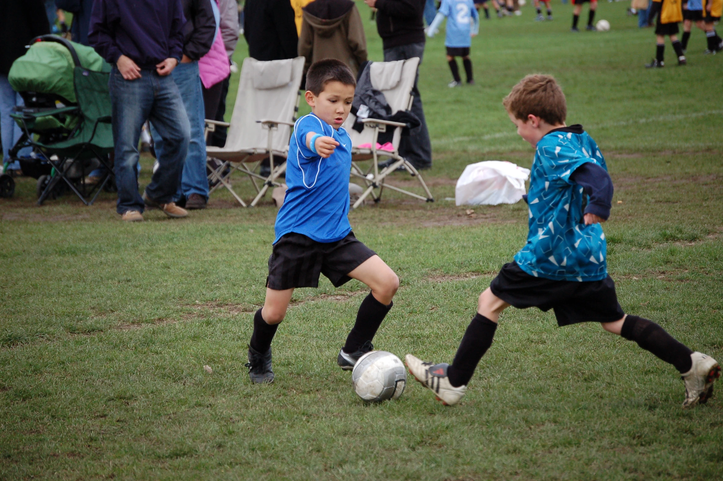 two children playing soccer while people watch