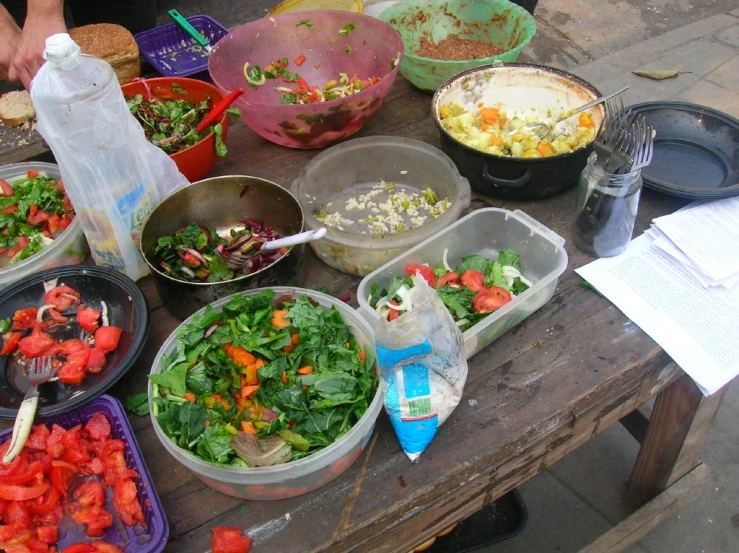 an outdoor food stand with multiple salad dishes on the table