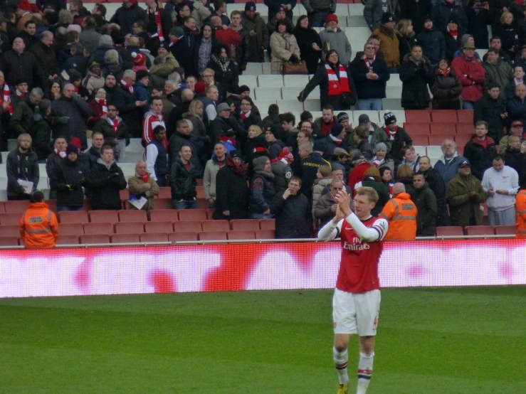 man in red and white shirt clapping for fans