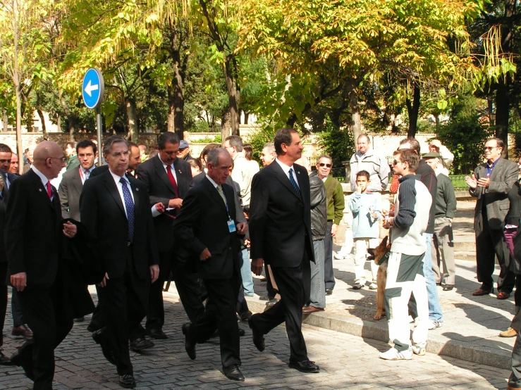 a group of men wearing suits and ties walk in the street