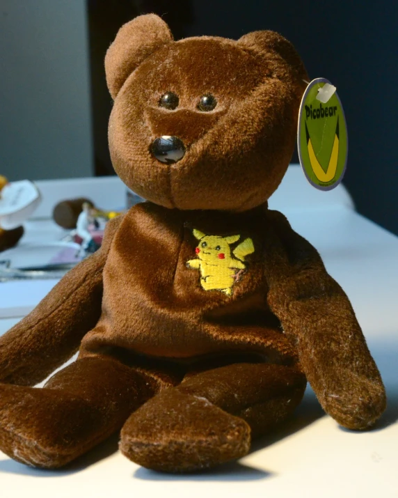 a brown teddy bear with a pikachu sticker on its chest