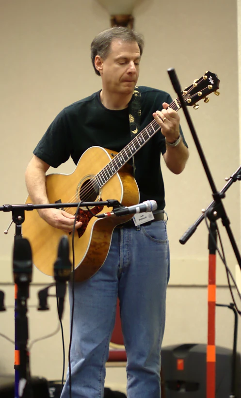 a man holding a guitar near a microphone