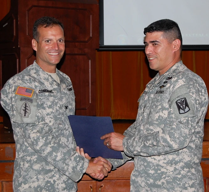 two military men are shaking hands at an event