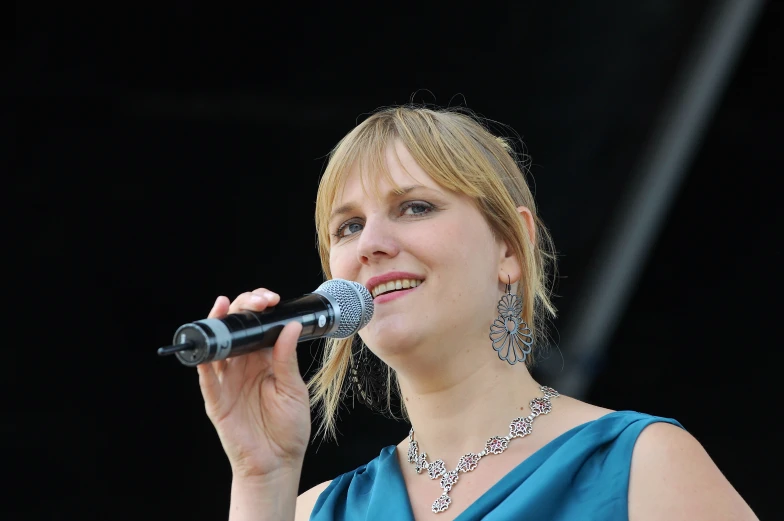 a blonde haired woman with a microphone in her hand