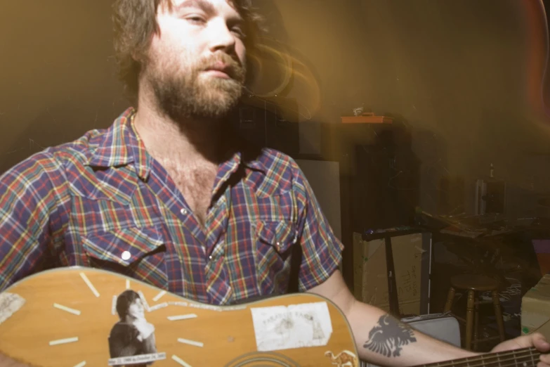 a man with a beard holding a wooden guitar