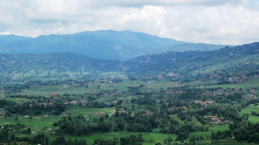 a green hillside and a lush landscape under clouds