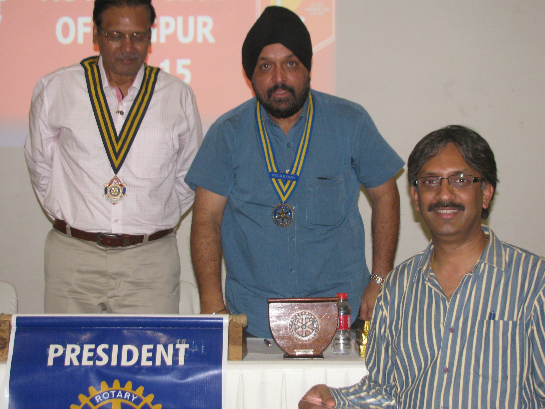 three men standing at a podium holding trophies