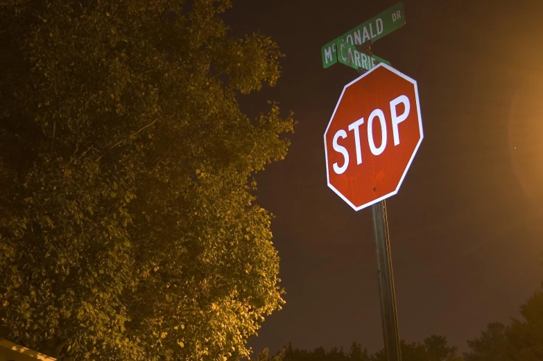 a lighted stop sign with two green street signs