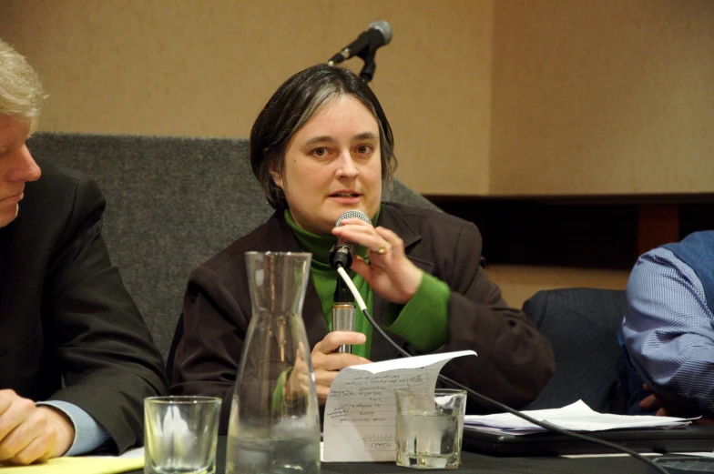 a woman wearing green is holding her microphone while speaking