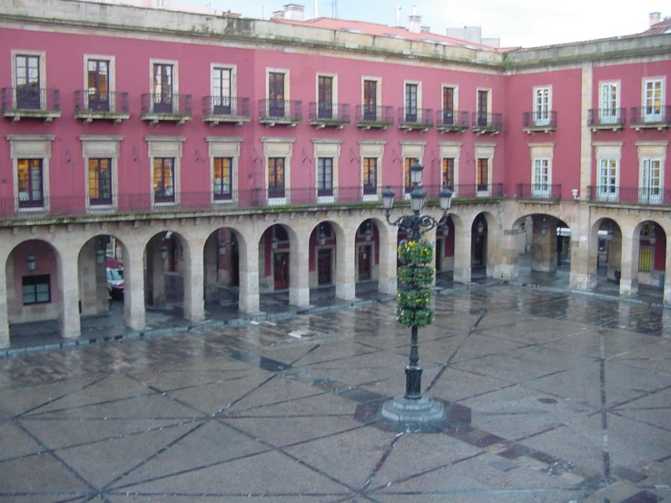 a pink courtyard with a statue standing in front of it