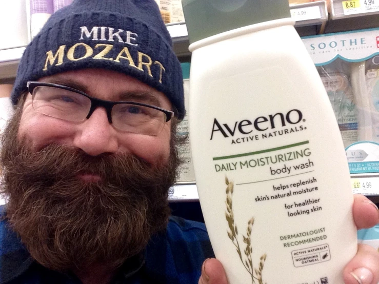 a man wearing glasses holds a bottle of shampoo while standing in a store aisle