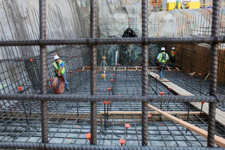 workers stand on the concrete inside of a caged area