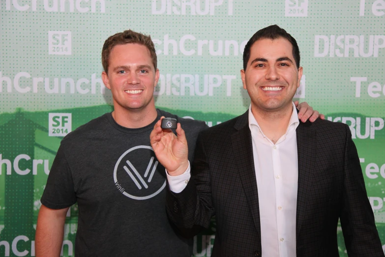 two men smiling while one man shows off his phone