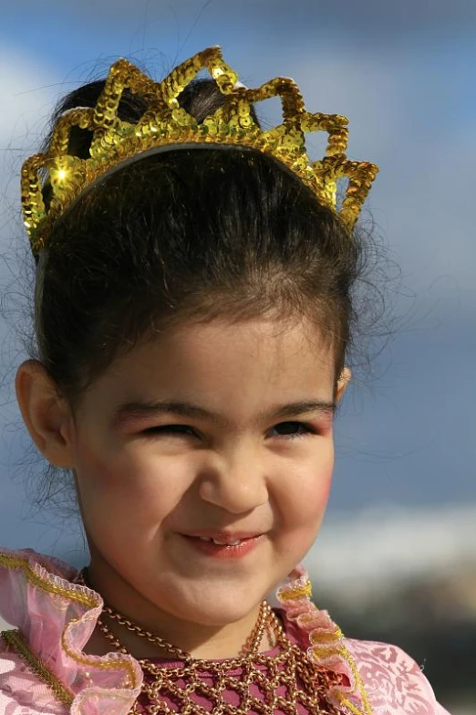  smiling wearing a gold tiara and pink dress