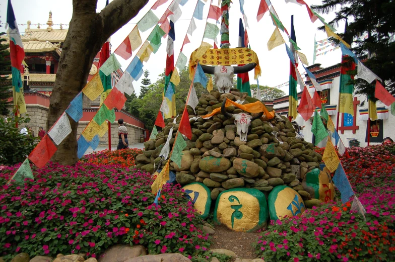 many flags and flowers decorate the landscape surrounding a tree and other colorful flowers