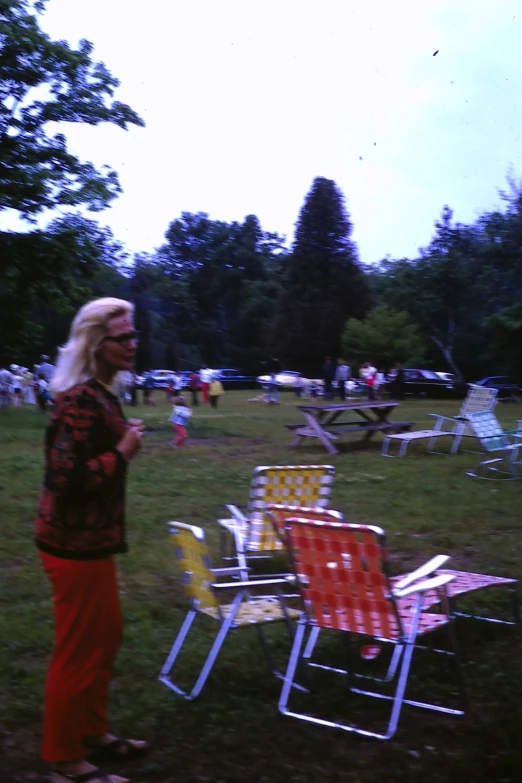 a woman standing in the grass looking at many different chairs