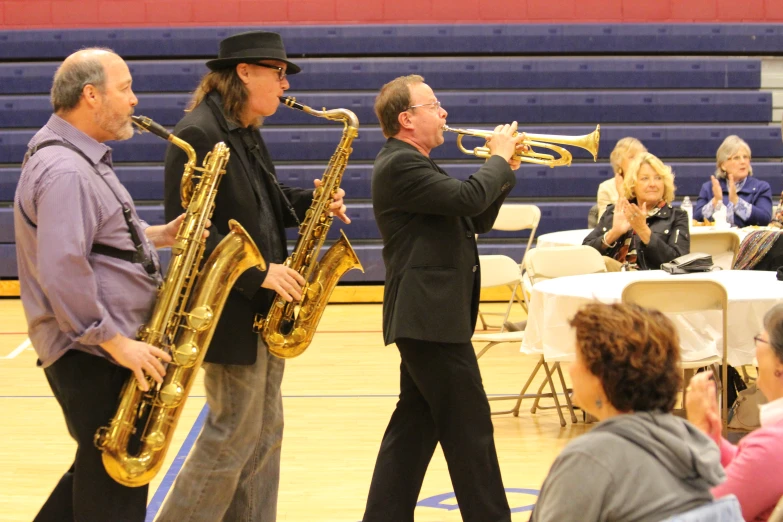 a couple of men playing instruments on top of a basketball court