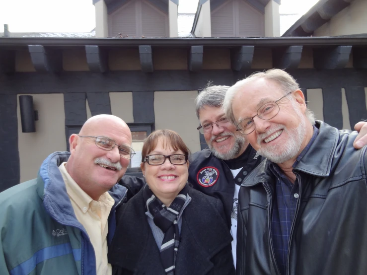 three men and one woman are posing for a po