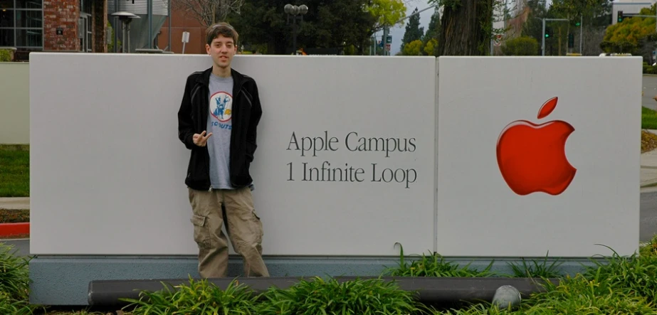 a man posing for a po in front of a sign with an apple