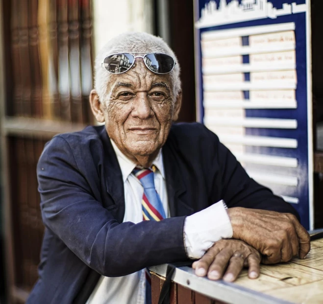 an older man with sunglasses leaning on a railing