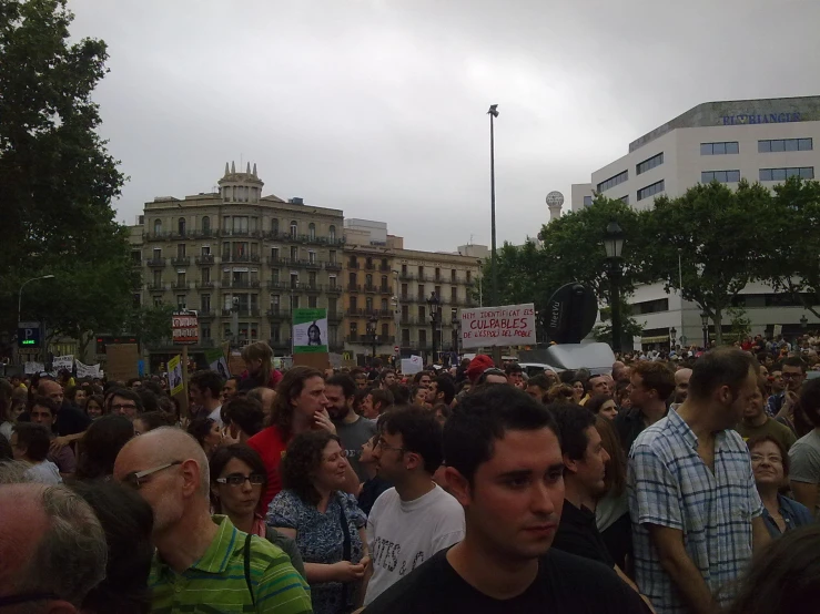 a large crowd is standing near some buildings
