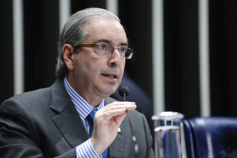 a man talking into a microphone in a suit and tie