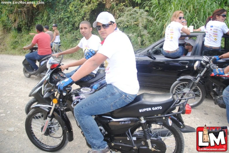 a man riding on the back of a motorcycle next to parked cars