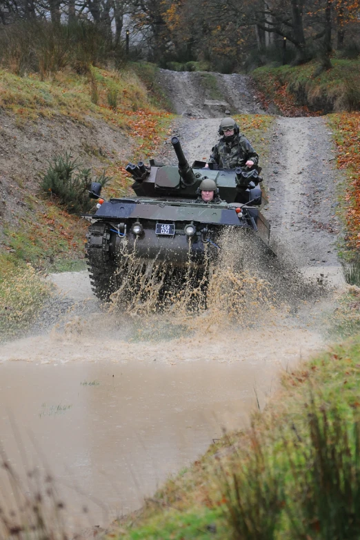 the tank is traveling in the mud through some water