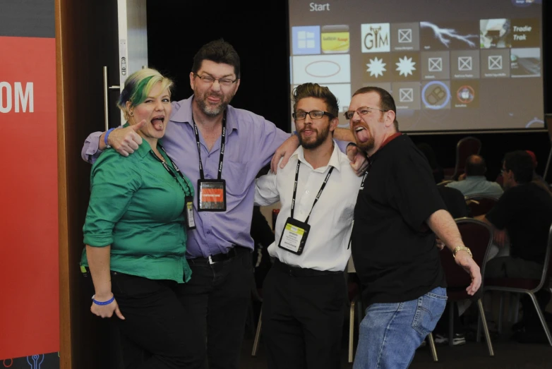 five smiling friends in front of a projection screen