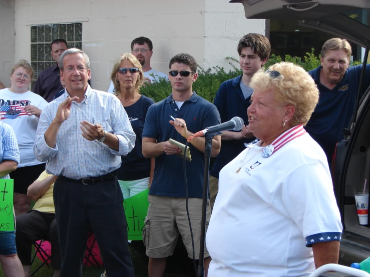 two people talking into microphones with others standing in front of them